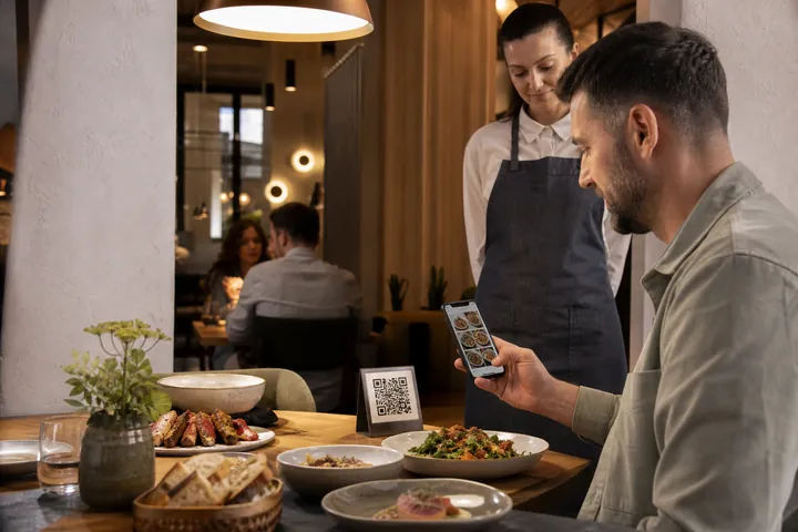 Un oaspete de restaurant care scanează un cod QR de masă și răsfoiește un meniu vizual de mâncare pe telefon